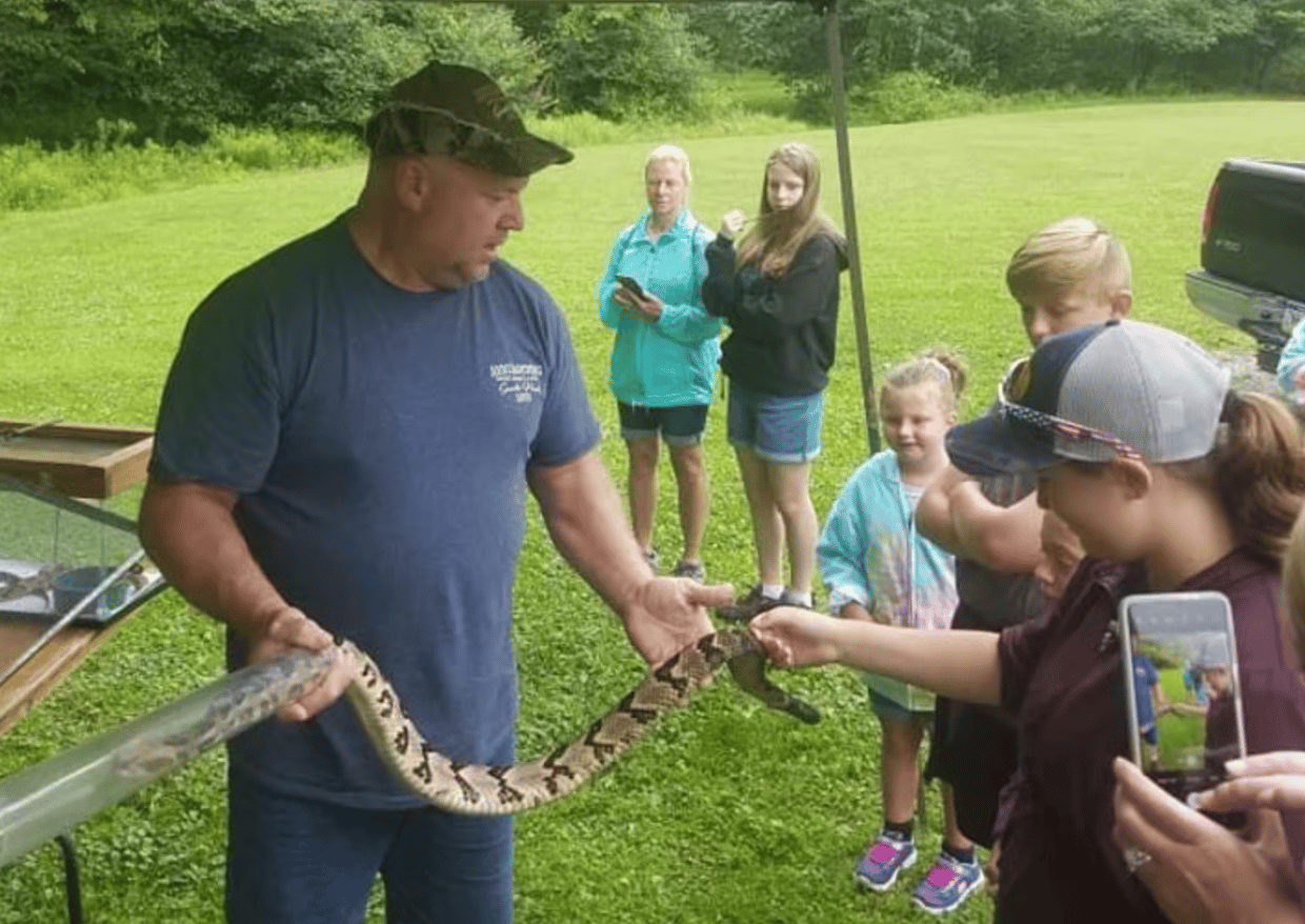 A man shows a snake to a crowd A man shows a snake to a crowd