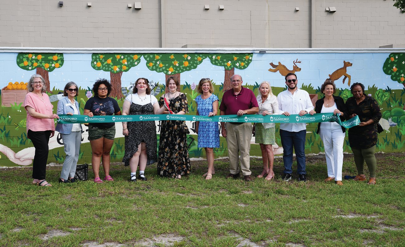group of 11 people at a ribbon cutting ceremony in front of a mural group of 11 people at a ribbon cutting ceremony in front of a mural