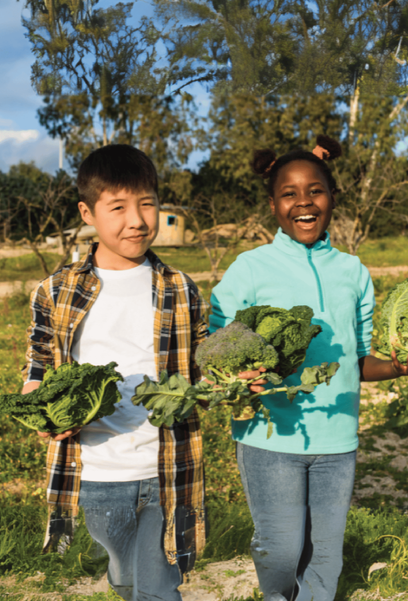 a boy and a girl holding vegetables outside