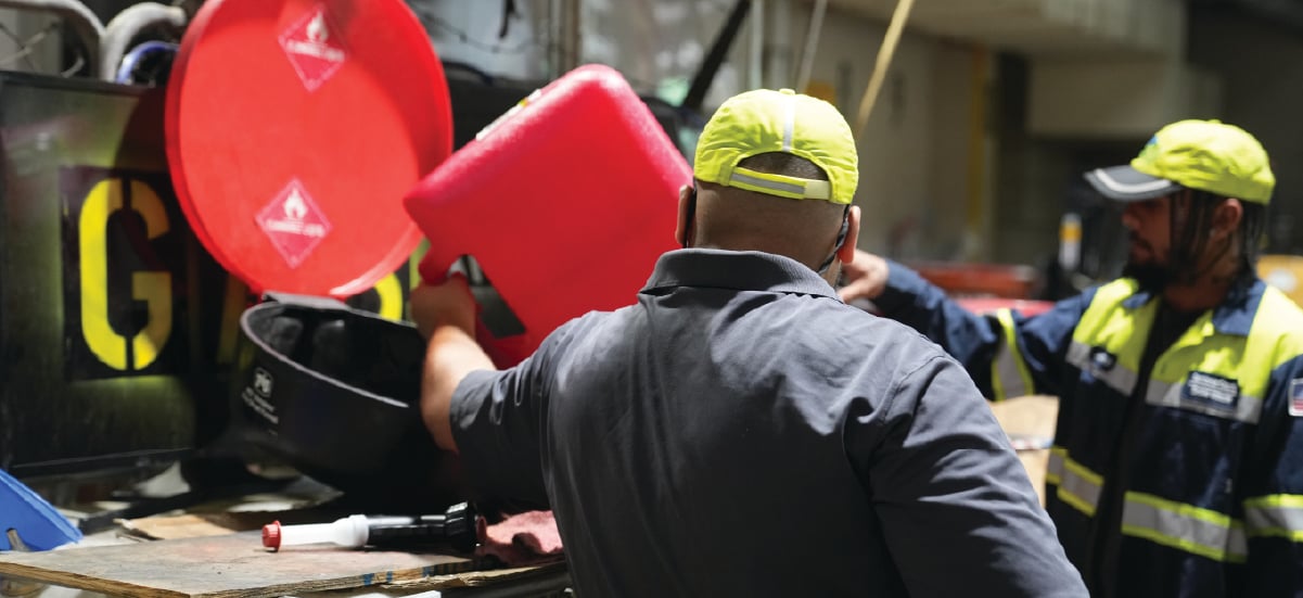 2 employees emptying a gasoline container 2 employees emptying a gasoline container