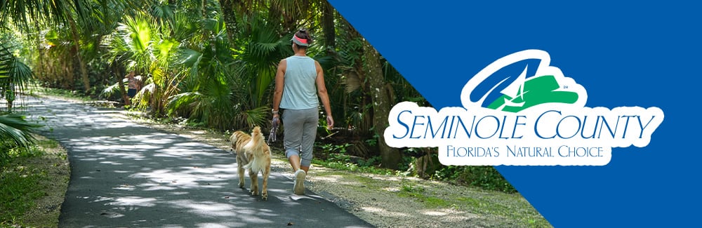 Women walking dog on trail with leash, with seminole county logo