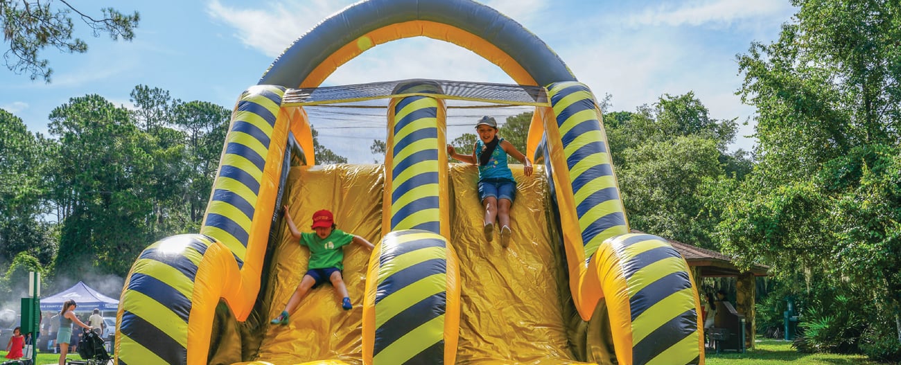 two kids outside going down inflatable slide two kids outside going down inflatable slide