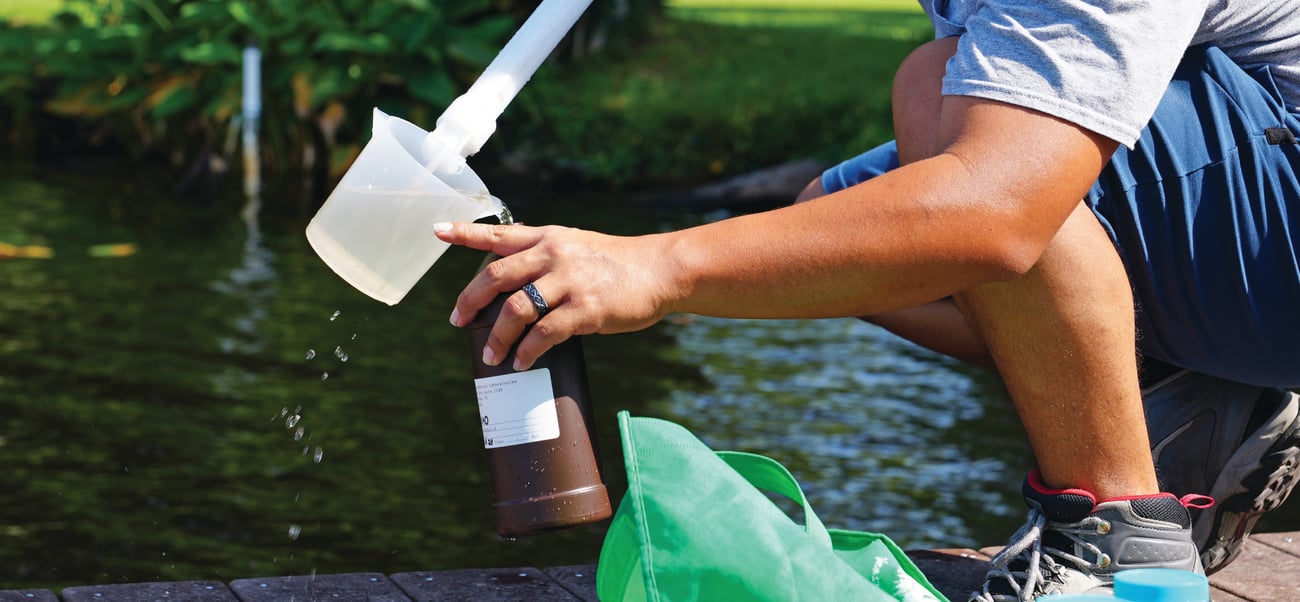worker grabing water from a lake to put in a testing bottle worker grabing water from a lake to put in a testing bottle