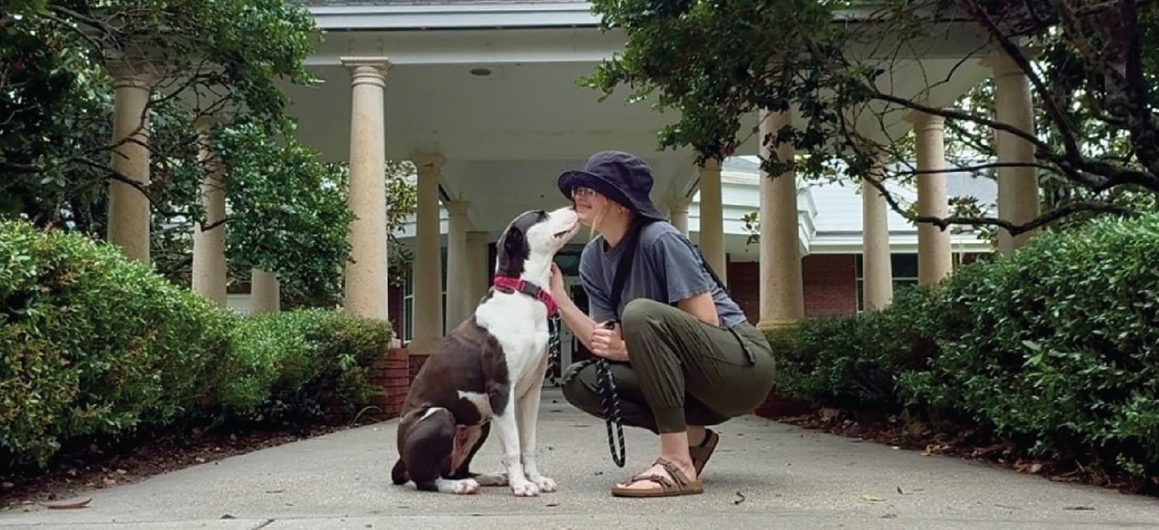 dog and volunteer girl sitting on a sidewalk outside of a building dog and volunteer girl sitting on a sidewalk outside of a building