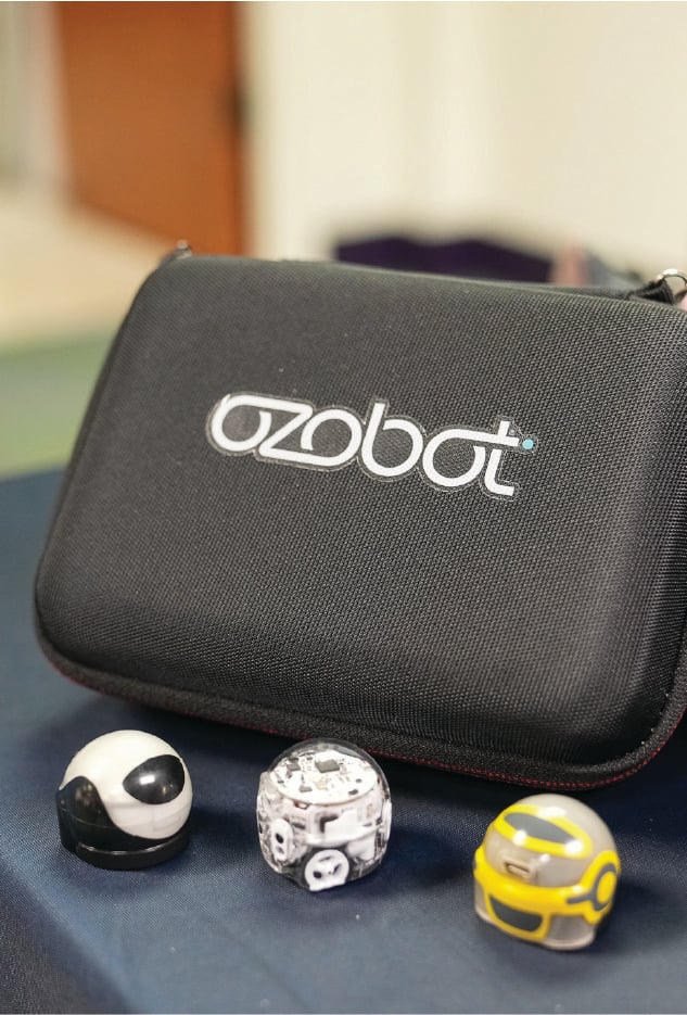 black ozobot box next to 3 ozobot toys (black, white, and yellow)