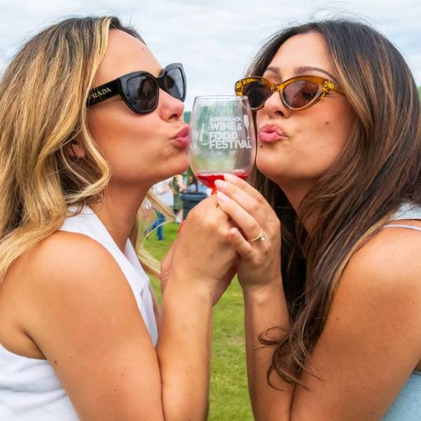 two women pose with wine glass