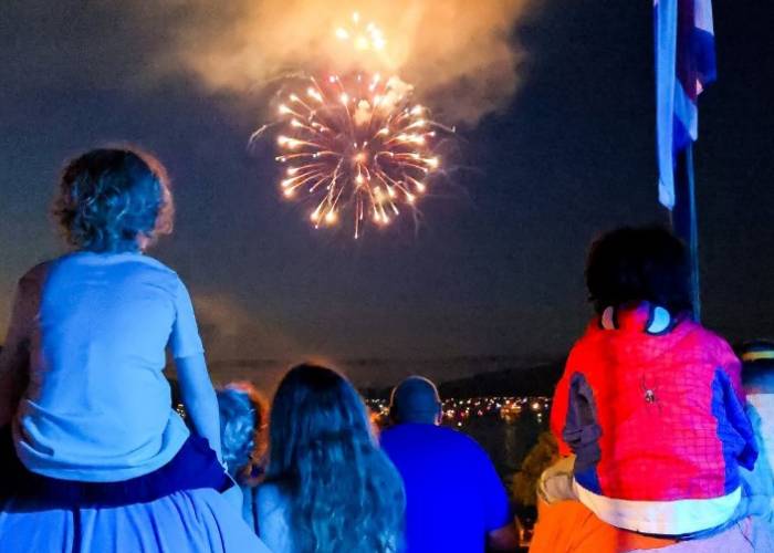 families watching fireworks with kids on shoulders