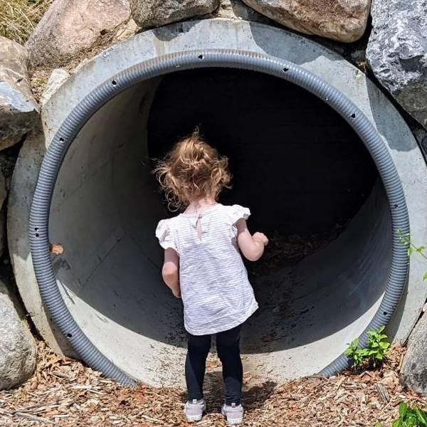 little girl looks into play tunnel