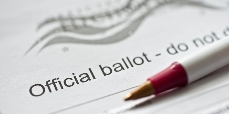 Photo of the top of a voting ballot with a pen laying on top of it.