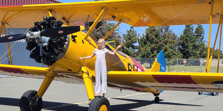 Photo of a child in front of propeller plane.