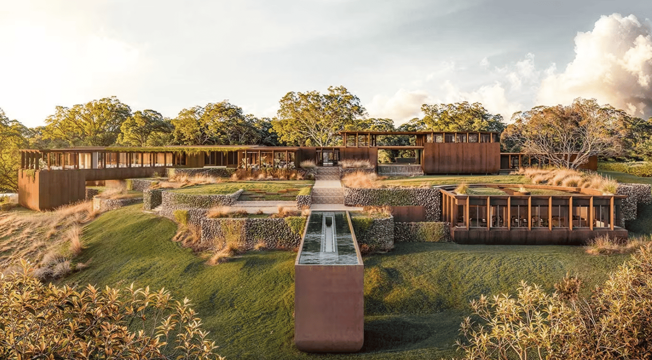A modern brown house with terraces, water feature, and landscaped gardens A modern brown house with terraces, water feature, and landscaped gardens