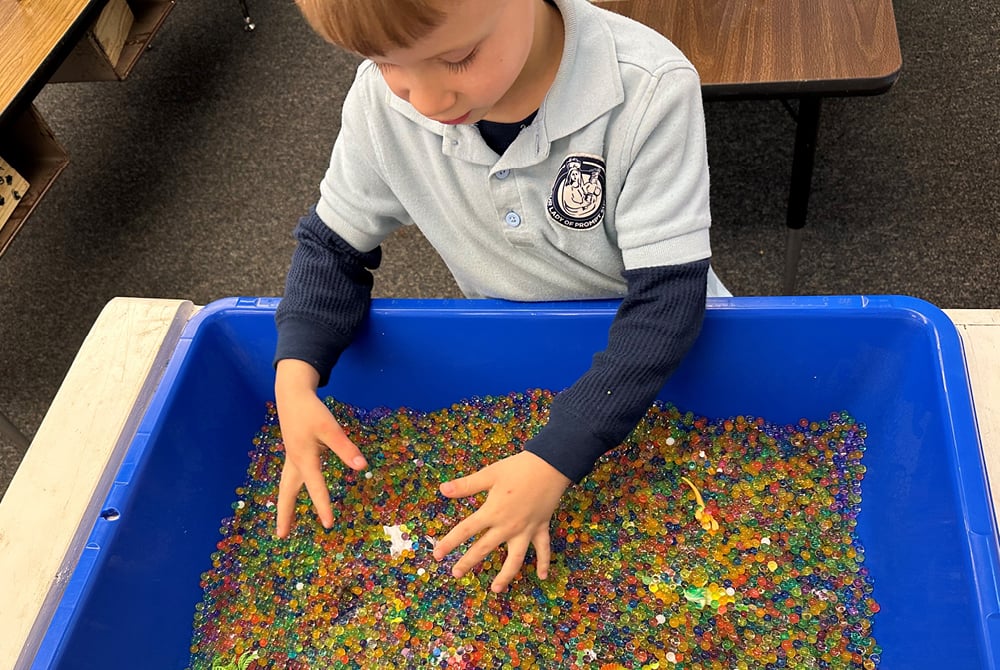 A child searches for hidden objects in water beads