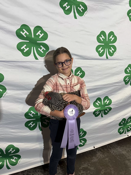 youth holding a chicken and her winning ribbon