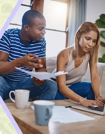 Young couple sitting next to each other on a couch, with papers, laptop and coffee cups on a small table in front of them Young couple sitting next to each other on a couch, with papers, laptop and coffee cups on a small table in front of them