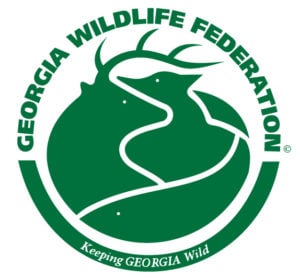 Logo of the Georgia Wildlife Federation in green and white. The circular emblem features negative space and interlocking silhouettes to depict various animals, including a deer with antlers, a bear, a bird, and a fish at the bottom. The text "GEORGIA WILDLIFE FEDERATION" arches over the top of the circle, and the tagline "Keeping GEORGIA Wild" is written along the bottom border.