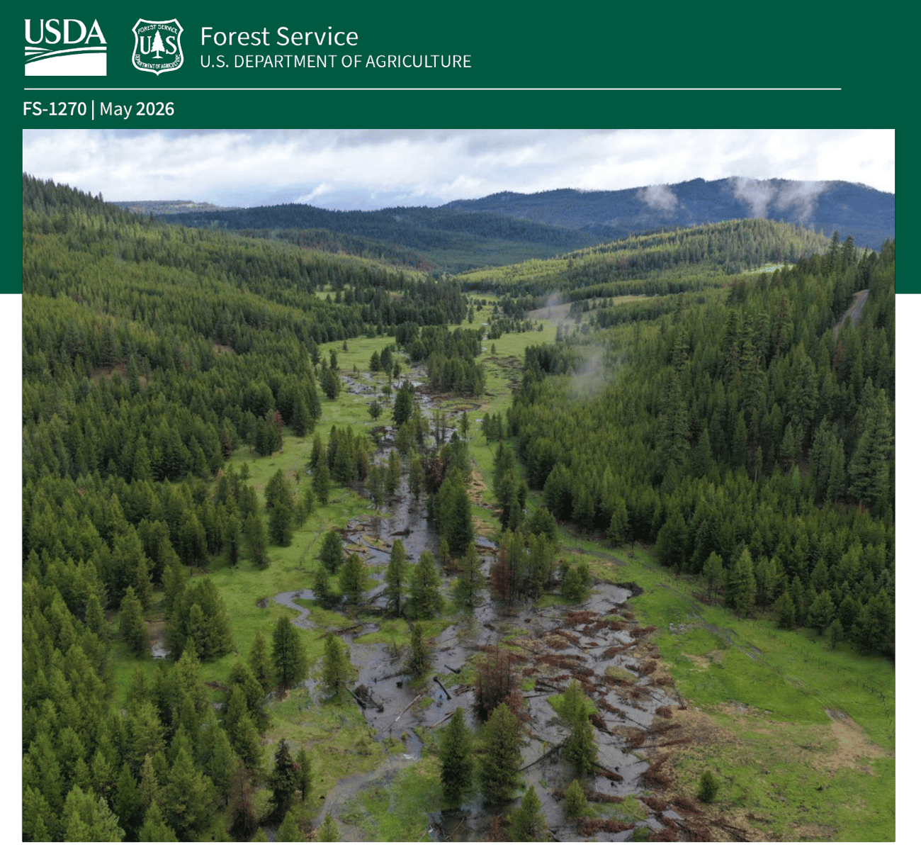 A document header from the USDA Forest Service, dated May 2026 (FS-1270), features a wide aerial view of a lush mountain valley. A winding stream flows through a grassy meadow littered with fallen logs and debris, surrounded by dense evergreen pine forests on both sides. In the distance, rolling green hills and forested mountains rise beneath a cloudy, overcast sky with patches of low-hanging mist.