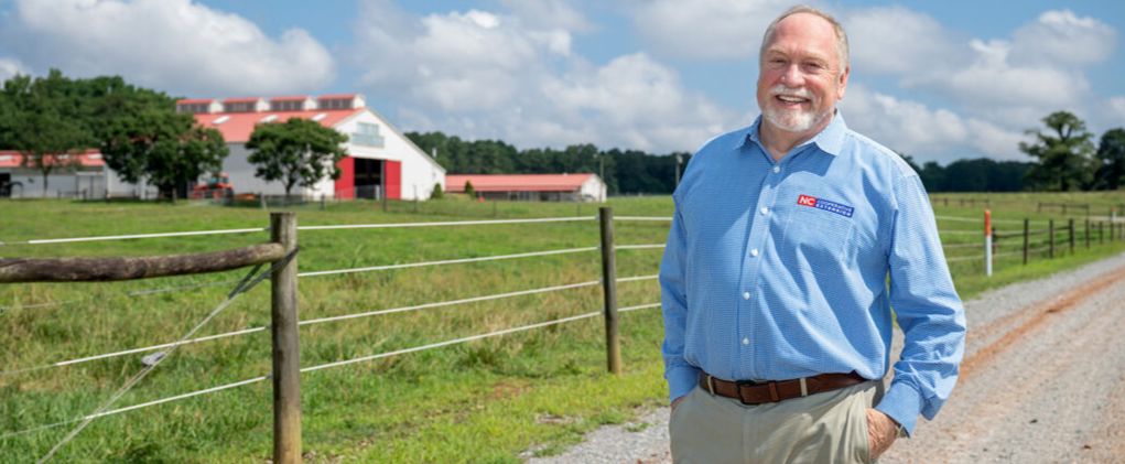 David Monks, NC State Extension director, stands on a dirt road outside a barn at NC State's Lake Wheeler Road Beef Education Unit.