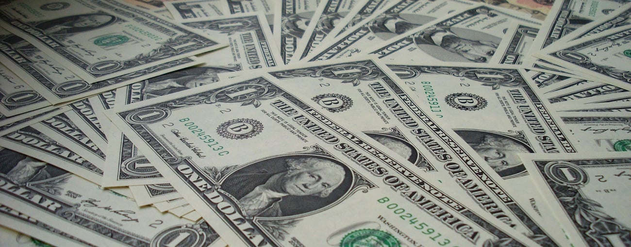 One dollar bills scattered across a flat surface One dollar bills scattered across a flat surface