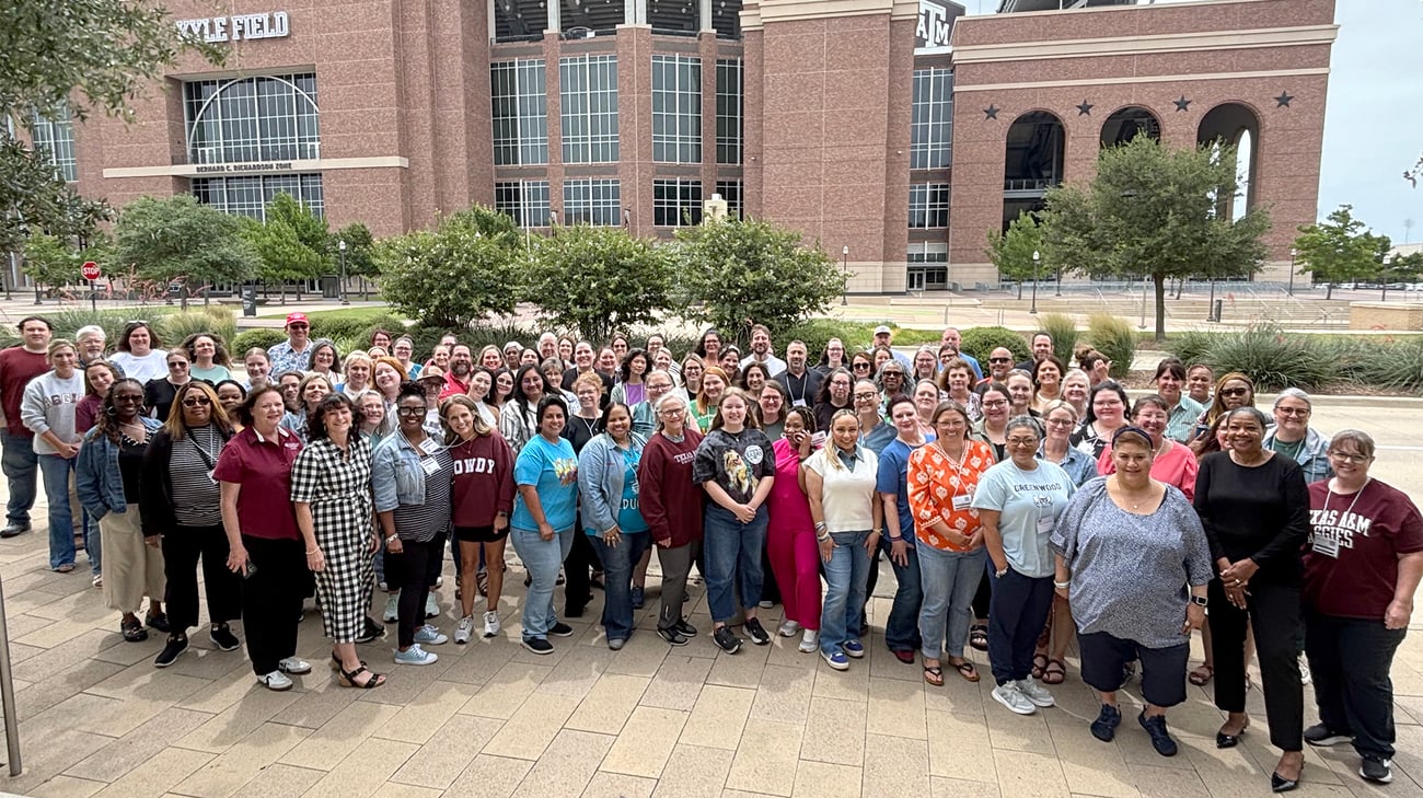 A large group of people stand in front of Kyle Field at Texas A&M University.