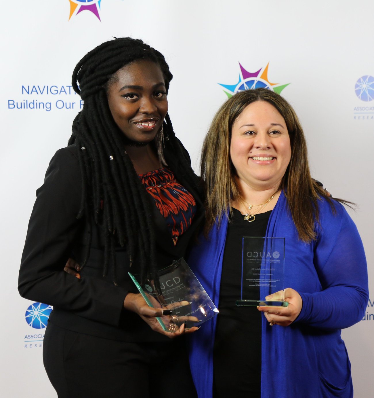 Two people smiling and holding an award.