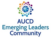 AUCD Emerging Leaders Community logo. A circular design made of multicolored dots surrounds a blue center featuring a stylized starburst graphic. Below the logo, the text reads “AUCD Emerging Leaders Community” in blue lettering. The design uses a range of bright colors, including purple, orange, green, and blue, on a light background.