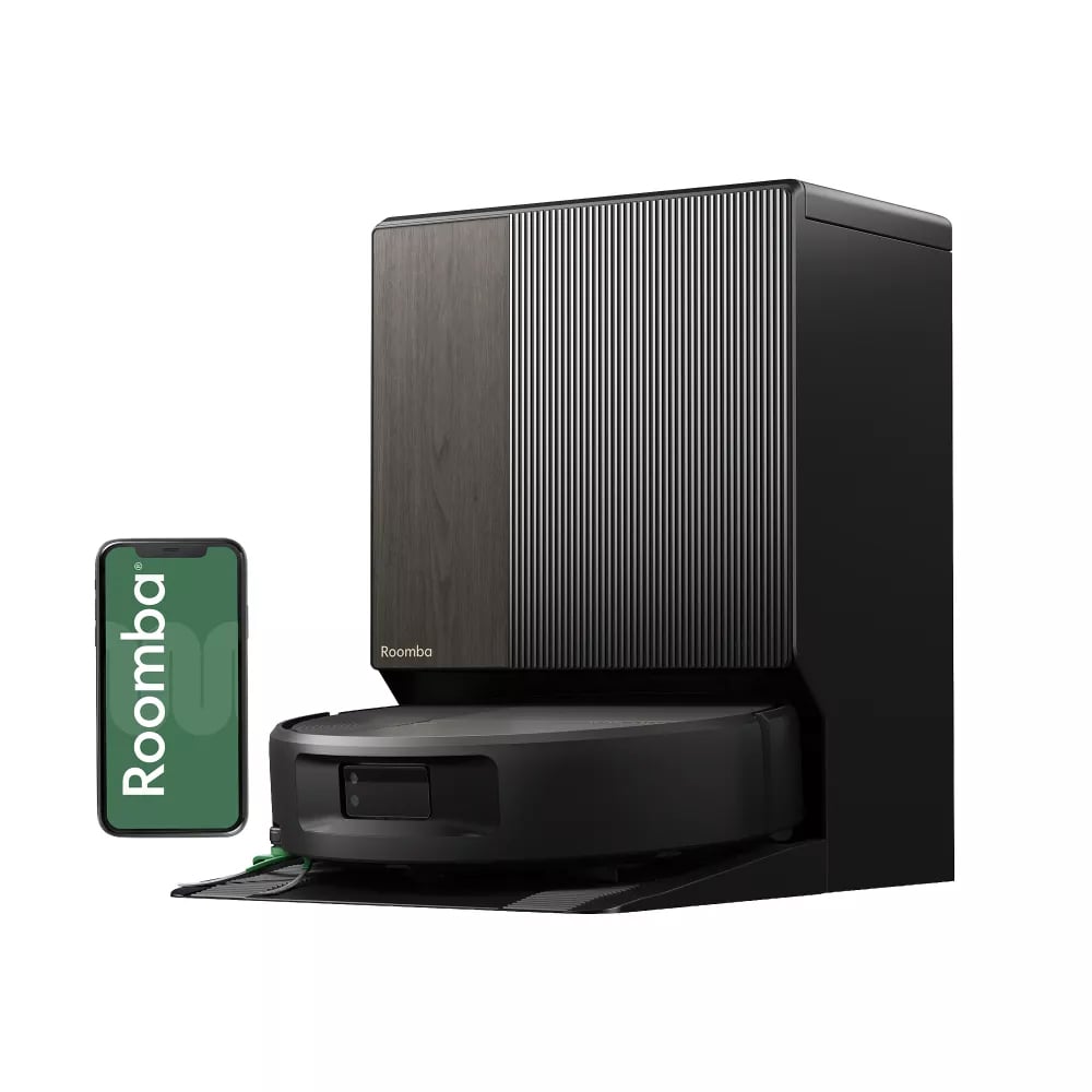 A black Roomba robot vacuum beside its charging dock and smartphone
