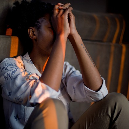 Woman resting her elbows on her knees with her hands in front of her face.