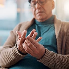 Older man holding his fingers in pain