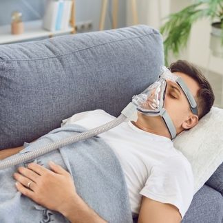 Man laying on a couch wearing a CPAP 