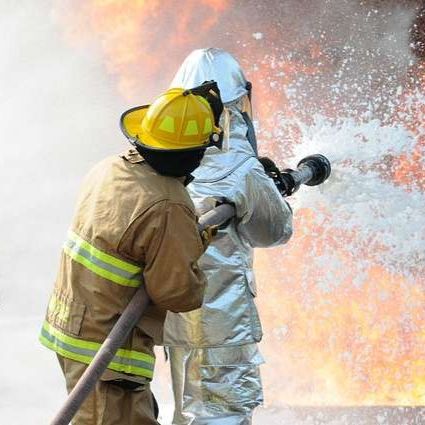 Two firefighters spraying water on a fire