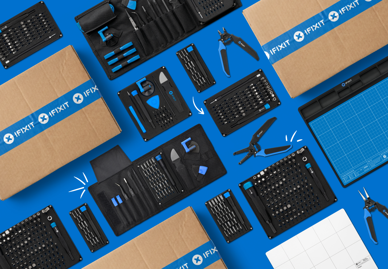 Flat lay of iFixit toolkits and shipping boxes arranged diagonally on iFixit blue background. The composition highlights a variety of pliers, bit kits, and a FixMat.