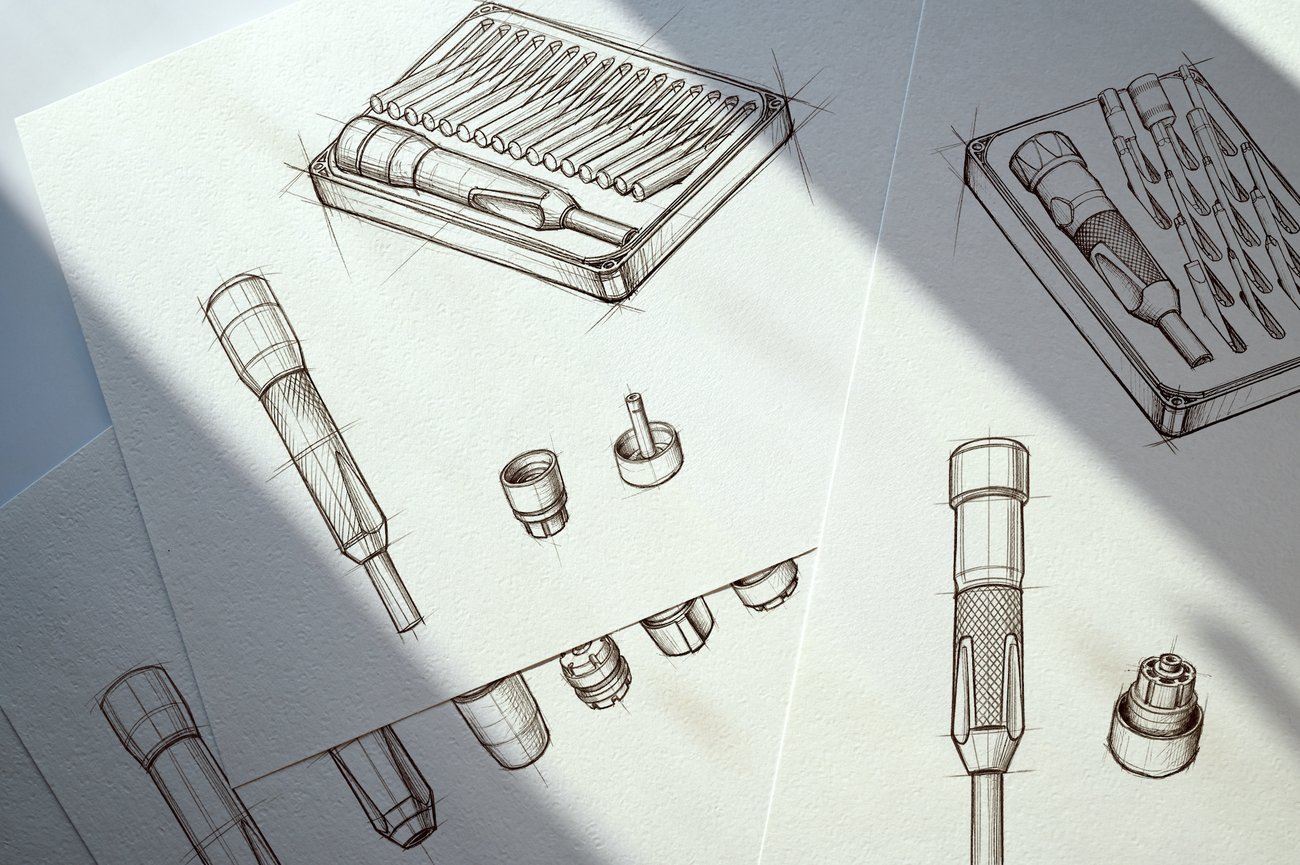 Product design sketches show an iFixit screwdriver kit, driver handles, bits, and component details drawn on overlapping sheets of paper, with diagonal sunlight creating a workshop concept feel.
