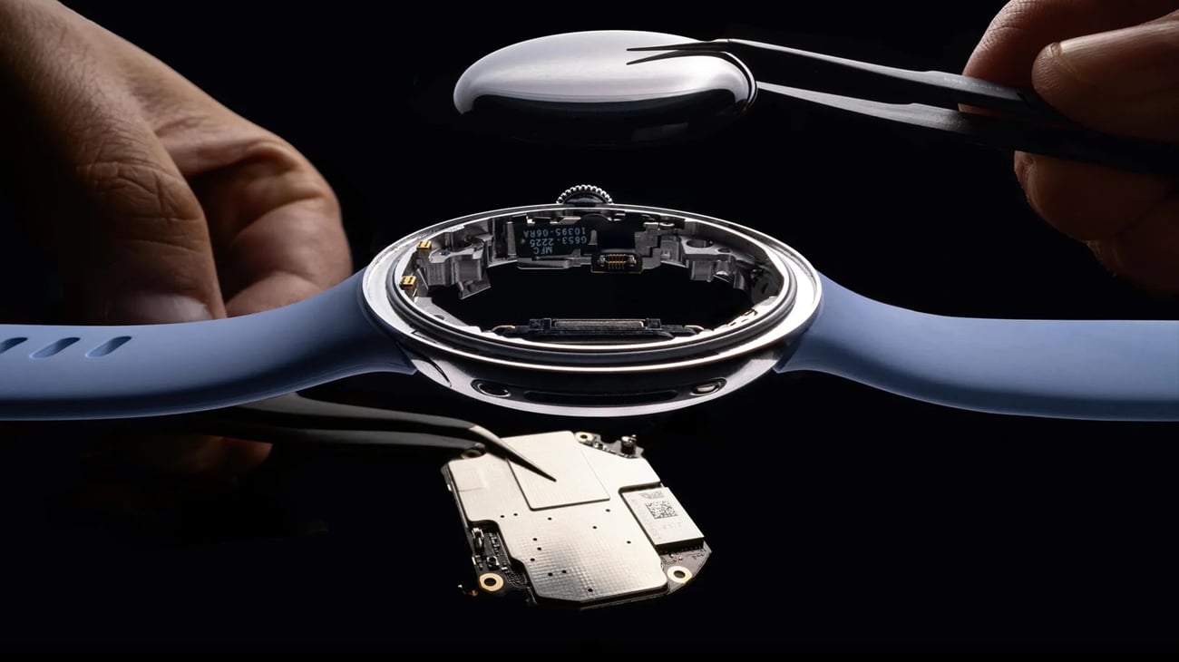 A deconstructed smartwatch is held by tweezers.