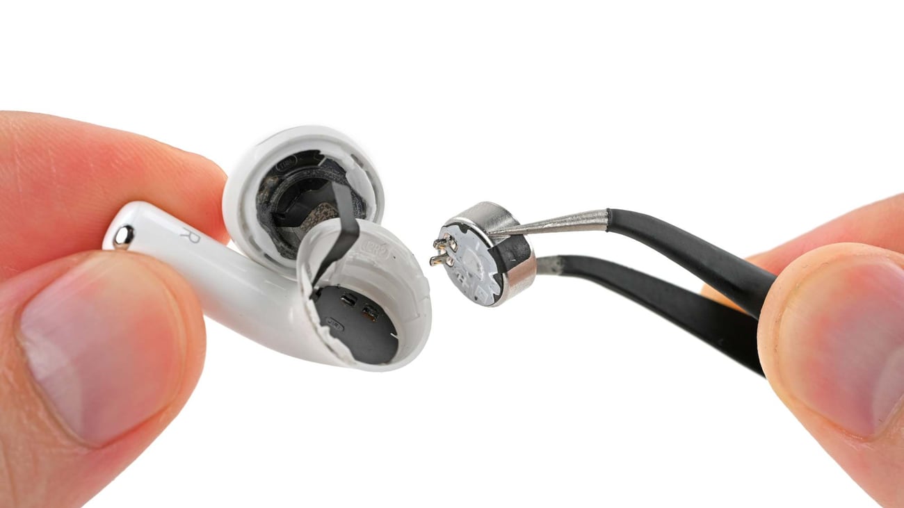 Removing the battery from an AirPods 5 earbud with tweezers
