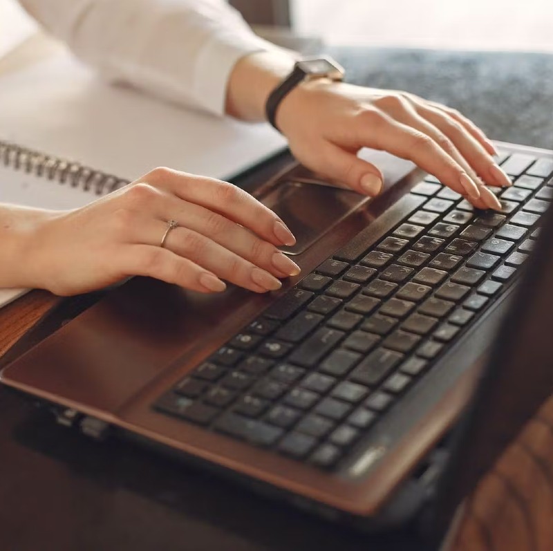 Close up photo of someone typing on a laptop