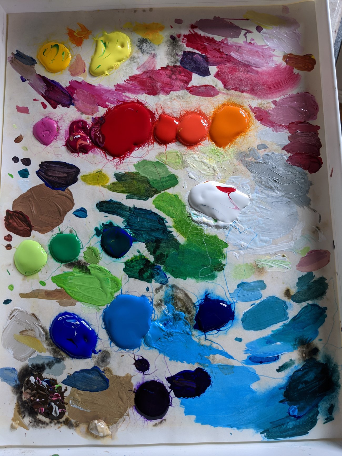 Artist palette covered with colorful blobs of acrylic paint.