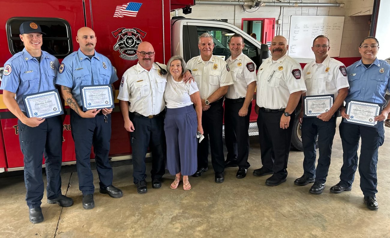 Employees posing with awards and Fire Chief Matt Kinley in front of fire engine at station.
