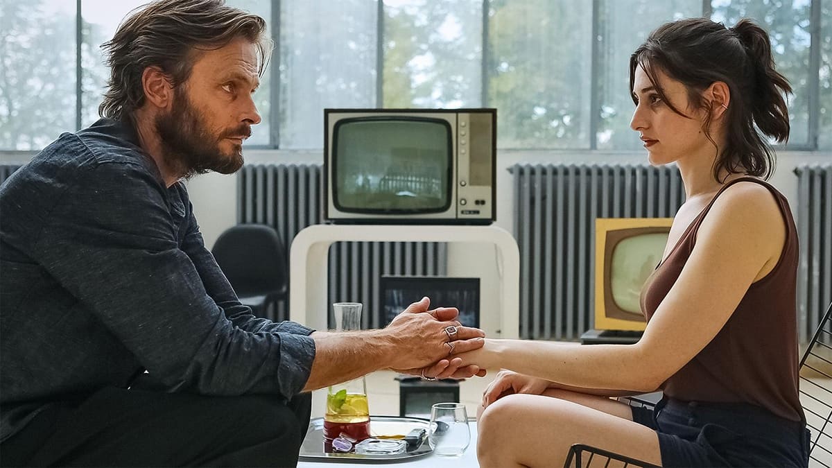 A man and woman sit facing each other holding hands A man and woman sit facing each other holding hands