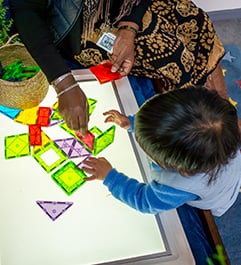 Child playing with magnetic tiles on a light table