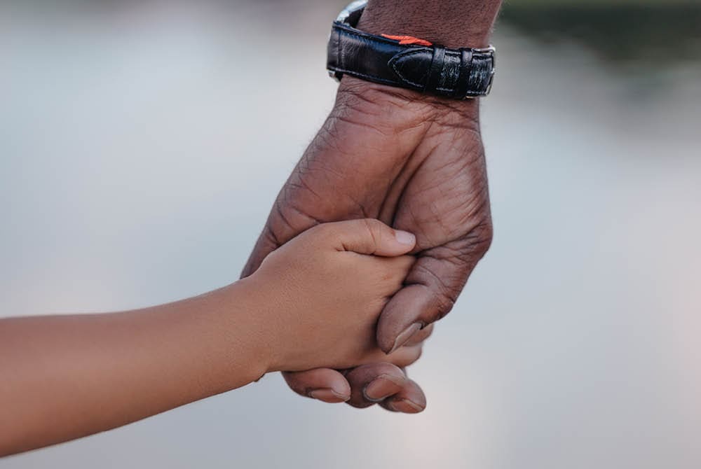 An adult and child holding hands