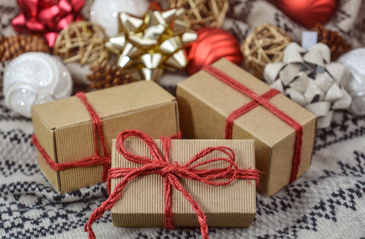 Small kraft paper wrapped packages with red ribbons and red, gold and white holiday bows. Small kraft paper wrapped packages with red ribbons and red, gold and white holiday bows.