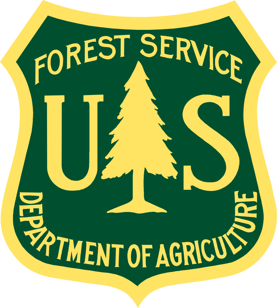 "The official shield-shaped logo of the United States Forest Service. The emblem features a dark green background with a gold border. In the center, a large gold coniferous tree is flanked by the letters "U" and "S" in a serif font. The words "FOREST SERVICE" are arched across the top, and "DEPARTMENT OF AGRICULTURE" is curved along the bottom edge, all in gold capital letters.