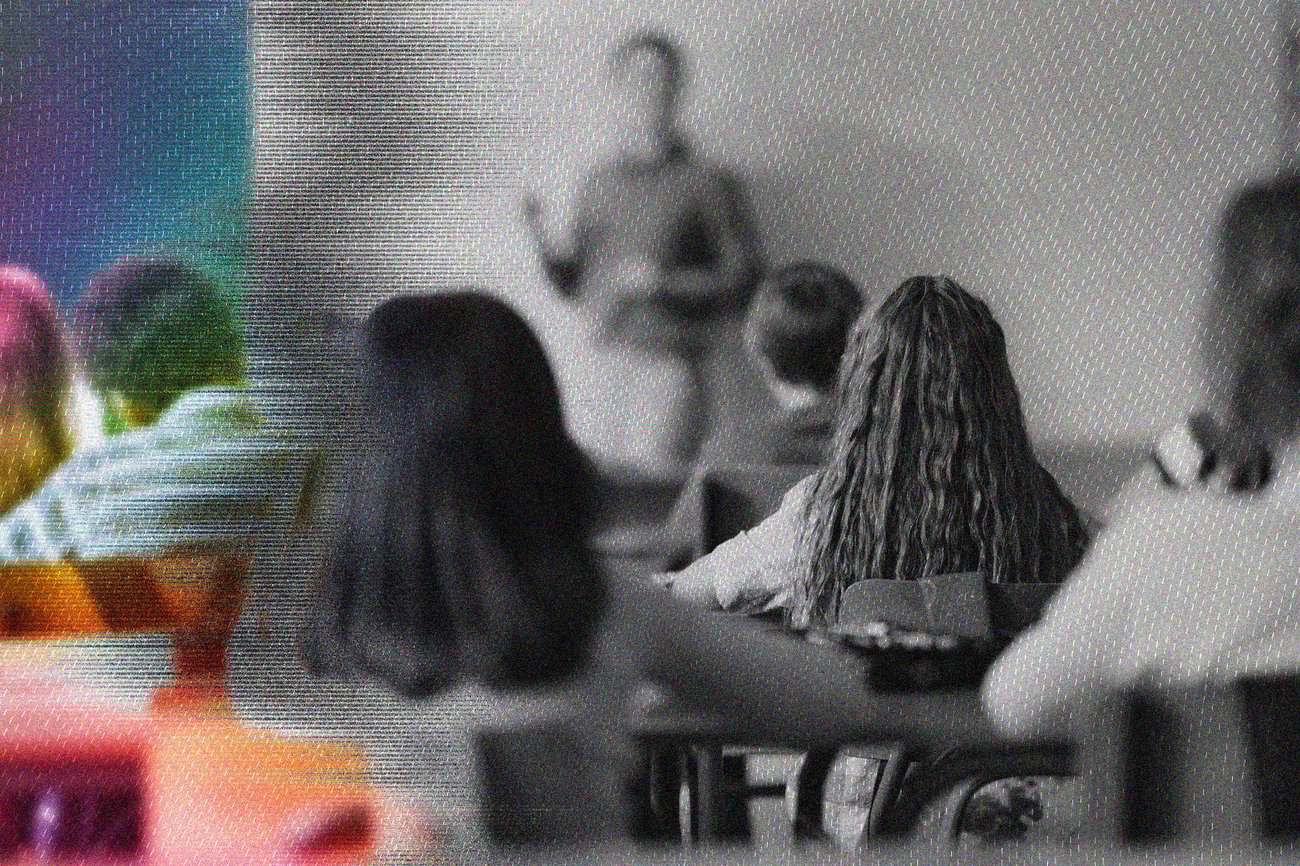 A photo of children in a classroom watching their teacher. Most of the photo is in black and white with some colour on the left side.