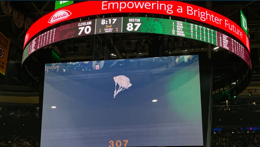 Photo of toy zebras parachuting on the jumbotron alongside a message from Takeda
