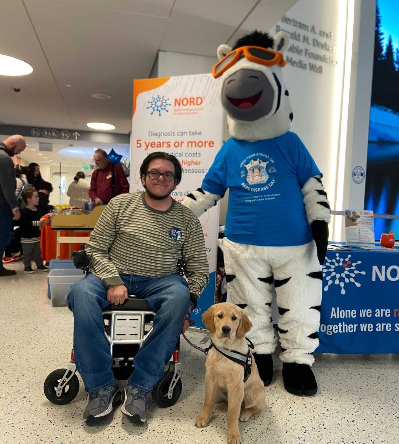 NORDY the Zebra posing with a rare community member and his service dog at Boston Children's Hospital