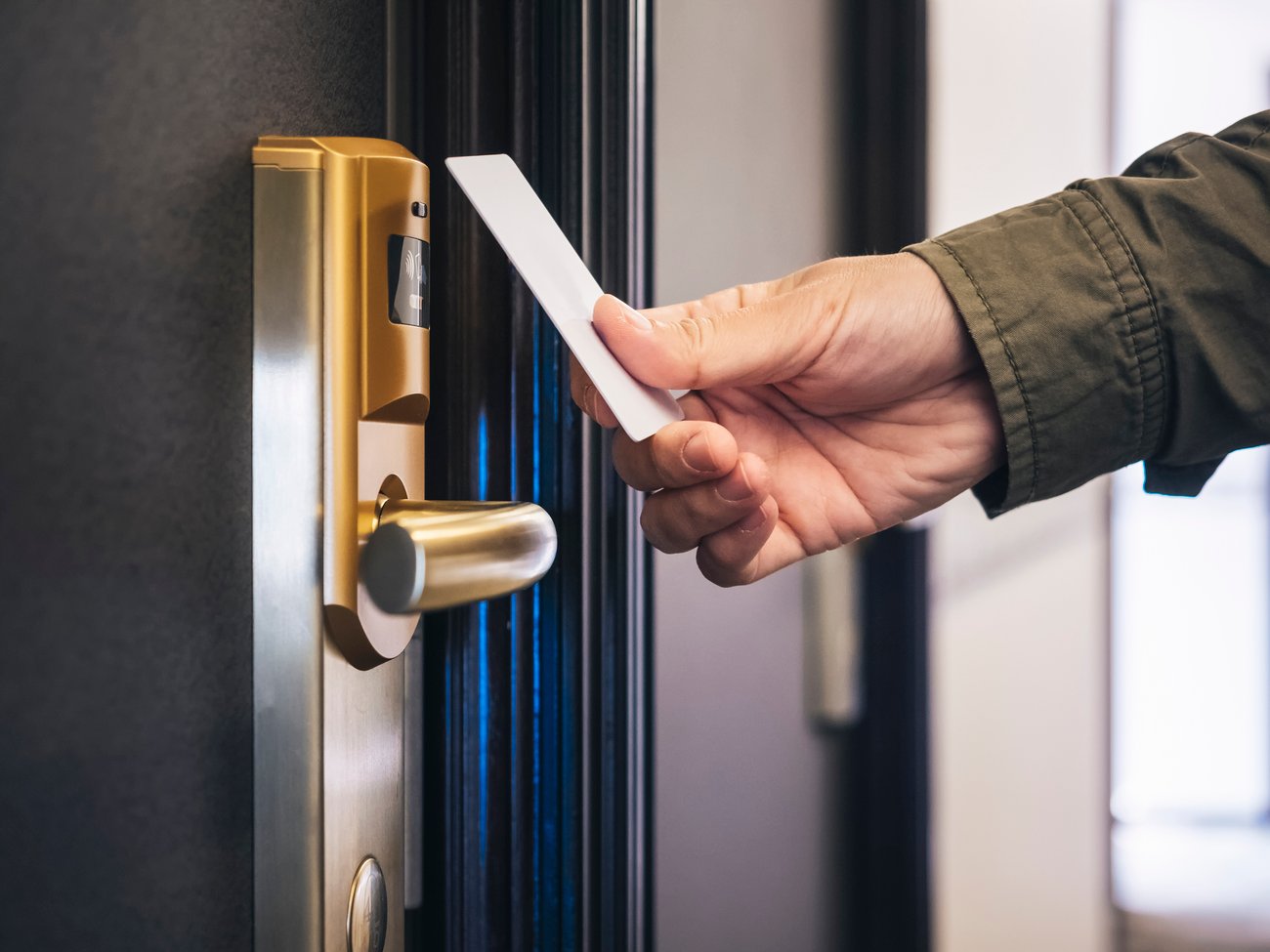 man's hand reaching out key card to get into hotel room