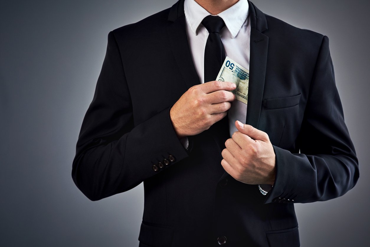 A business man puts money into his jacket