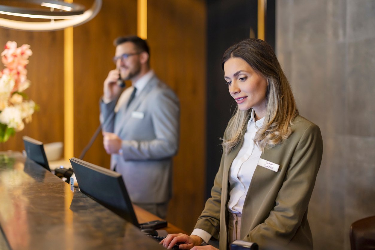 Two hotel employees working at the front desk