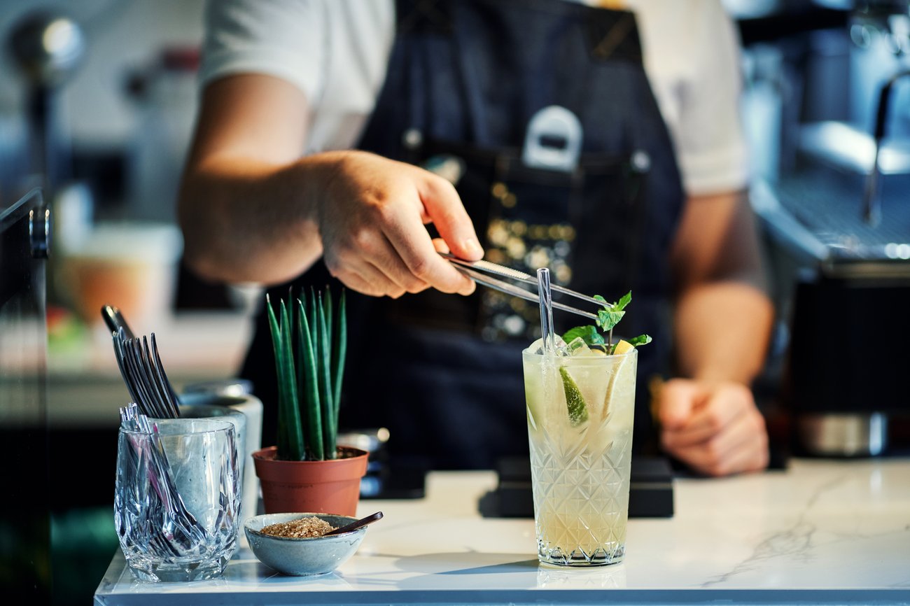 a bartender garnishes a cocktail with a sprig of mint