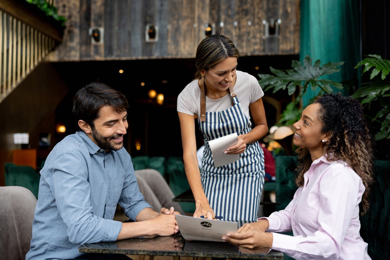 couple at a restaurant ask the waitress about the menu